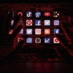 Mãos sombrias alcançando ícones de redes sociais no computador