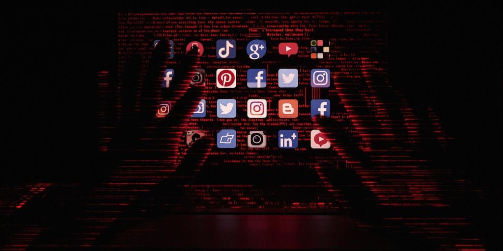 Mãos sombrias alcançando ícones de redes sociais no computador