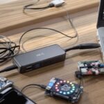 Vários hubs USB-C conectados a laptop em mesa de madeira
