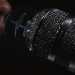 Microfone de estúdio com ondas sonoras e um rosto difuso.