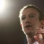 Zuckerberg gesticulando, semblante sério, em conferência de imprensa.