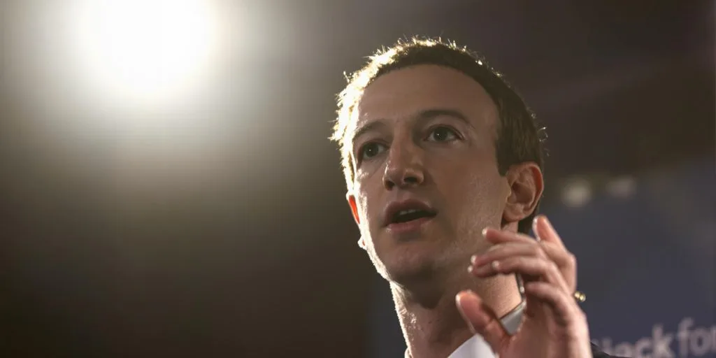 Zuckerberg gesticulando, semblante sério, em conferência de imprensa.